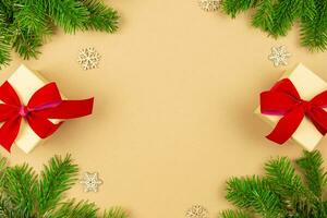 Christmas border flat lay with gift boxes and red ribbon decoration, xmas tree branches on craft paper background. Festive styled mockup composition. Top view. Copy space. photo