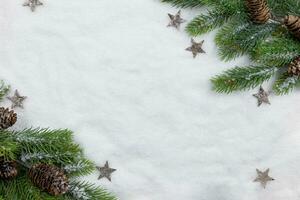 Christmas fir tree branches flat lay with pine cones and decoration on snow background. Creative composition with border. Top view. Copy space. photo