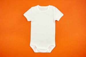 White baby girl or boy bodysuit mockup flat lay on orange background. Design onesie template, print presentation mock up. Top view. photo