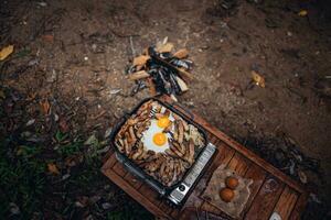 Fried eggs and grilled pork in a camping pan photo