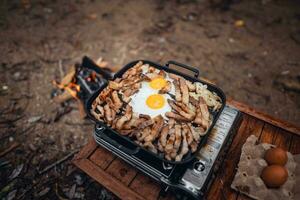 Fried eggs and grilled pork in a camping pan photo