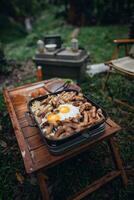 Fried eggs and grilled pork in a camping pan photo