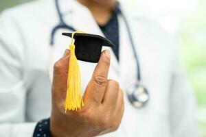 Asian doctor study learn with graduation gap hat in hospital ward, clever bright genius education medicine concept. photo