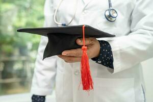 Asian doctor study learn with graduation gap hat in hospital ward, clever bright genius education medicine concept. photo