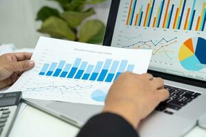 Asian accountant working and analyzing financial reports project accounting with chart graph in modern office, finance and business concept. photo