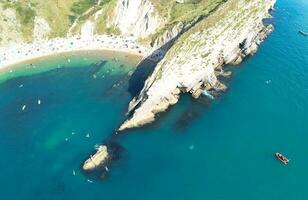 People at Most Beautiful High Angle View of British Landscape and Sea View of Durdle Door Beach of England Great Britain, UK. Image Was captured with Drone's camera on September 9th, 2023 photo