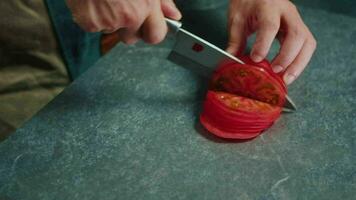 The cook slices the tomatoes with a sharp knife. Side view video