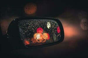 Night city lights reflecting in a car mirror covered in droplets after rain, east sussex, uk. photo