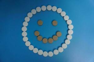 Positive smile made of pills on blue background. Concept of medicine, pills, treatment, medical insurance. happy concept photo