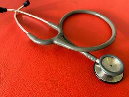 Stethoscope on red leather background, close up. Space for text. concept of health and medicine. National Health Day concept. photo