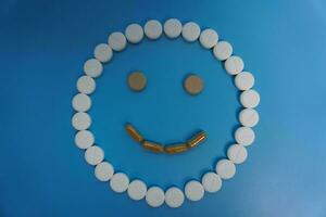 Positive smile made of pills on blue background. Concept of medicine, pills, treatment, medical insurance. happy concept photo