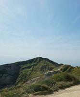 High Angle View of People are Approaching to Durdle Door Beach Which is Most Famous Tourist Attraction Place Through Walking Distance over Landscape and Hills. Captured on September 9th, 2023 photo