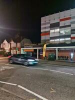 Low Angle View of Illuminated Road and Car Park Building Opposite of Luton and Dunstable Hospital at Luton City of England UK During night of Sep 3rd, 2023. photo