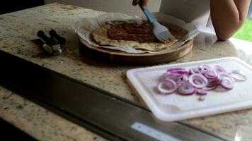 Mädchen von 6 Jahre alt ist vorbereiten Pizza mit Tomaten Soße und violett Zwiebel im Vorderseite von ihr Abonnenten. video