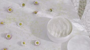 a white container of cream on a table with flowers video