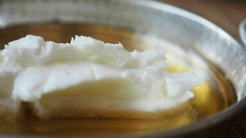 butter cream and honey in a bowl on table . video