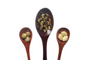 Top view variety of vitamins, minerals, and fish oil in pill form on a wooden spoon isolated on a white or transparent background. Dietary food supplements are a new alternative to health care. png