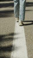 Girl in painted pants and sneakers walking on road markings, vertical video