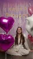 Girl with balloons in pajamas for her birthday smiling, vertical video