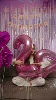 Girl sitting with big balloons with numbers 24, birthday party vertical video