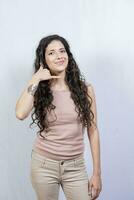 joven mujer haciendo teléfono gesto con dedos. joven niña haciendo teléfono gesto aislado, concepto de personas haciendo teléfono gesto en blanco antecedentes foto