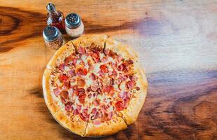 Top view of ham and cheese pizza on wooden table. Ham pizza with cheese edge on wooden background photo