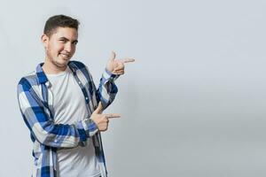 Smiling teenager pointing fingers to the side. smiling handsome man recommending something with his fingers. Caucasian handsome guy pointing his finger at a blank space photo