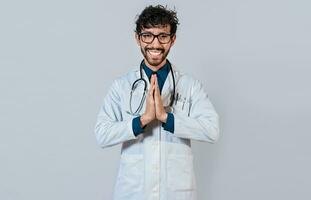 joven médico con palmas juntos. sonriente médico poniendo palmas juntos en aislado antecedentes. hermoso médico con manos juntos aislado. foto