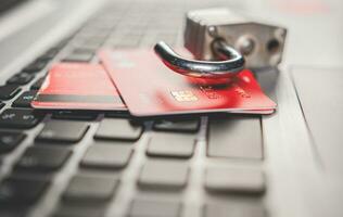 Online vulnerability concept with credit card. Credit card cyber security concept. Padlock on top of credit card on computer keyboard photo