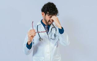 Overworked doctor with eyestrain isolated. Doctor holding glasses with burning eyes photo