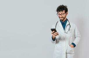 Smiling doctor using cellphone isolated. Young doctor with phone isolated, Doctor with phone on isolated background photo