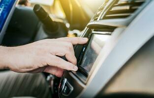 Close up of hands changing the car radio station. Concept of driver tuning the radio. Driver man changing radio station, Driver hands changing the radio station photo