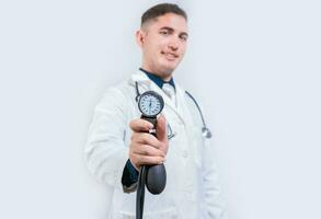 Latin doctor showing blood pressure monitor isolated. Young doctor holding tensiometer on isolated background photo
