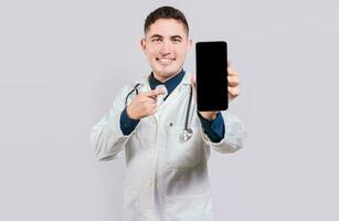 Smiling doctor showing an app on cell phone screen. Happy young doctor showing cell phone screen isolated photo