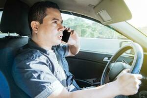 Concept of man calling on the phone while driving, A man driver calling on the phone in his car, Close up of a young man sitting inside car using mobile phone photo