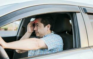 A driver with a headache in traffic, fatigued driver stuck in traffic, concept of a fatigued man in his car, stressed out. A suffering person with a headache in traffic photo