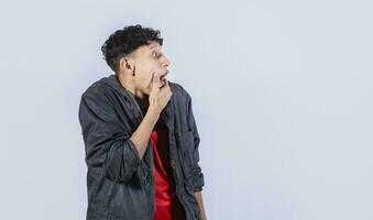 Amazed young man with hand near open mouth, man looking aside with face scared expression, surprised guy on isolated background photo