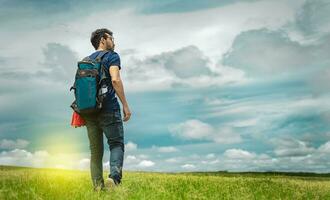 Adventurous man in the field, man with backpack in the field looking photo