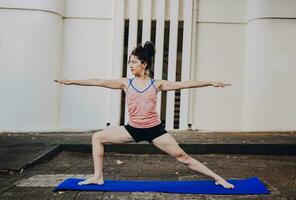 Girl practicing yoga Warrior II pose outdoors. Latin woman doing yoga warrior pose outdoors. Young woman doing yoga virabhadrasana II outdoors photo