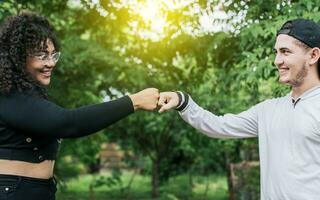 Two young teenage girls bumping their fists outdoors, Two smiling friends bumping their fists, concept of friendship fist bumping photo