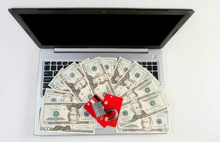 Top view of padlock with credit card on top of dollars on laptop keyboard. Padlock on top of credit card over dollar bills on computer keyboard photo