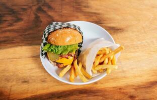 grande hamburguesa con queso con francés papas fritas servido en de madera mesa. delicioso hecho en casa hamburguesa en un plato en un de madera mesa foto