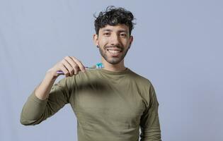 Close up of man holding a dental brush isolated, Handsome man holding dental brush. Tooth brushing and care concept. Smiling guy holding dental brush isolated. Oral and dental smile concept photo