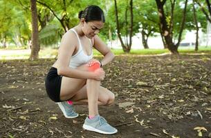 Athlete woman with knee muscle pain. Athlete girl on the ground with knee pain outdoors. Runner woman with knee pain outdoors. Athlete knee pain and fractures concept photo