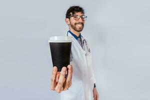 Smiling doctor showing coffee to go isolated. Friendly doctor showing coffee to go isolated photo