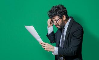 Businessman puzzled with documents in hand isolated, Confused businessman with documents in hand, Concept of man in formal suit frustrated with documents in hand photo