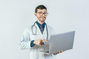 Smiling doctor using and pointing laptop isolated. Young doctor in glasses using laptop and looking at camera. Handsome doctor using laptop isolated photo