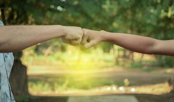 Two young men clashing their fists, image of two young men bumping their fists in a friendly way, close up of two fists bumping in a friendly way photo