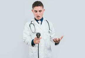 asombrado joven médico con sangre presión monitor aislado. sorprendido médico mirando a tensiómetro en blanco antecedentes foto