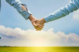 Close up of a couple holding hands, Concept of couple hands holding hands, Hands together of a couple in the field photo